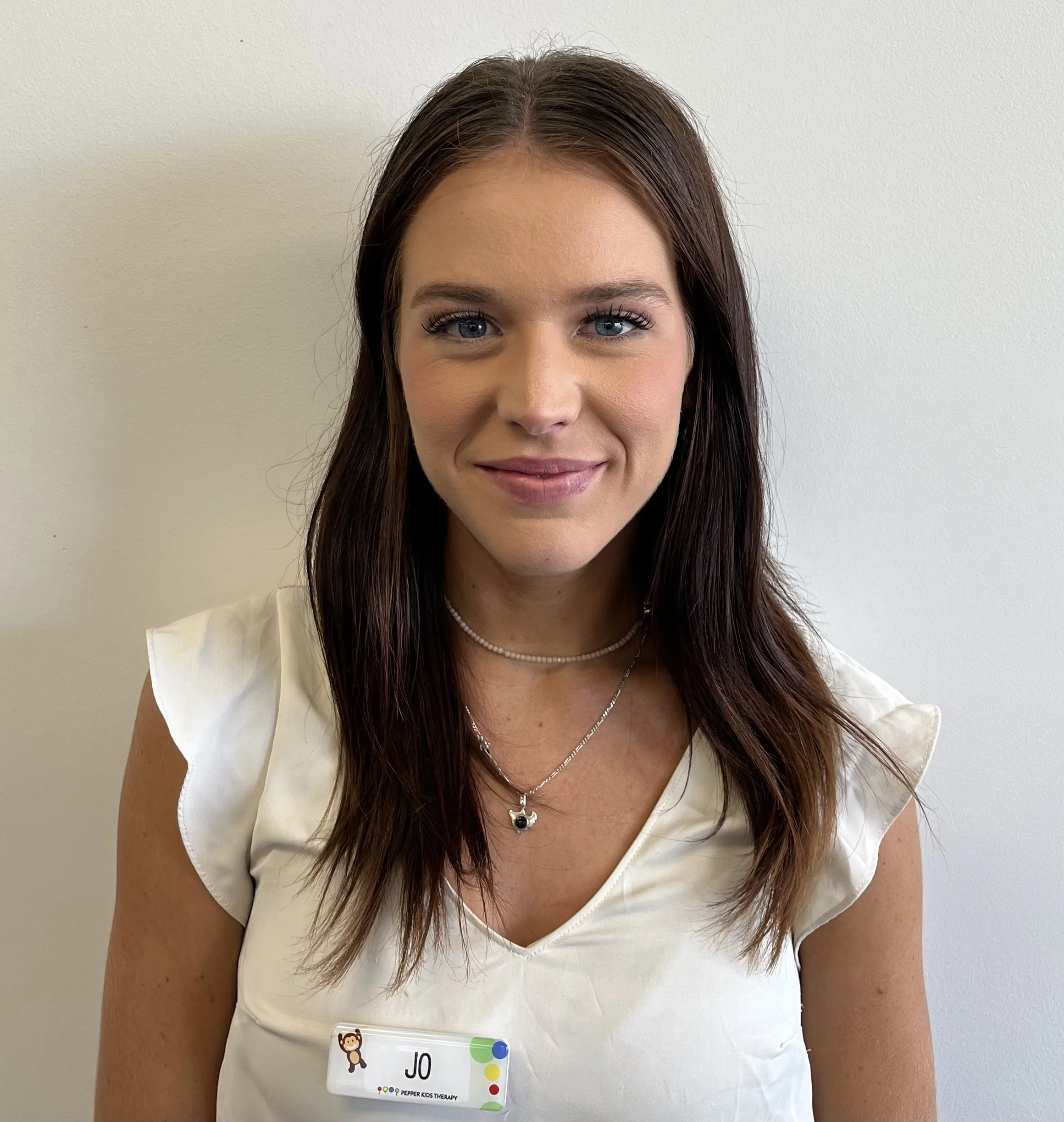 A woman, Alana, wearing a white shirt and a necklace.