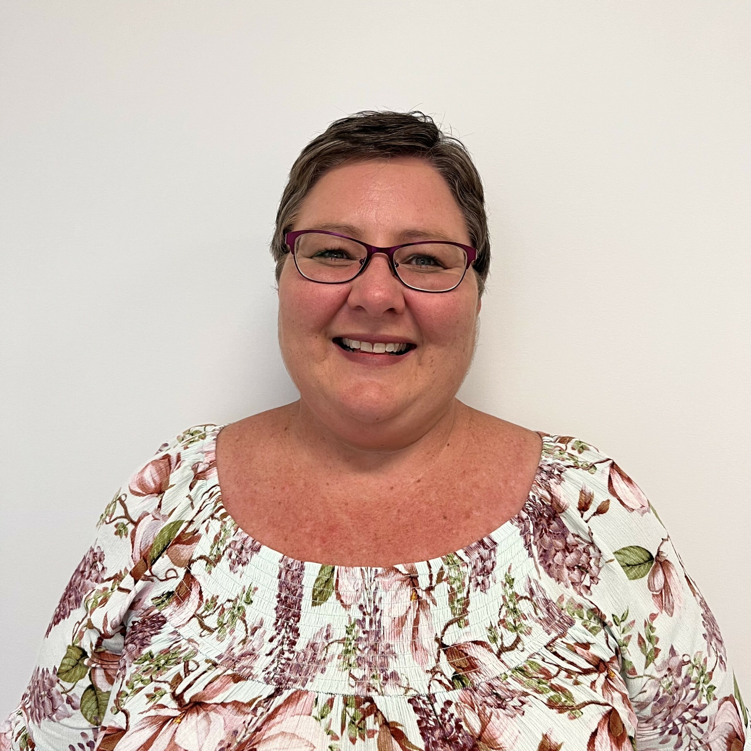 Ronel Van Der Westhuizen, a woman wearing glasses and a floral top.