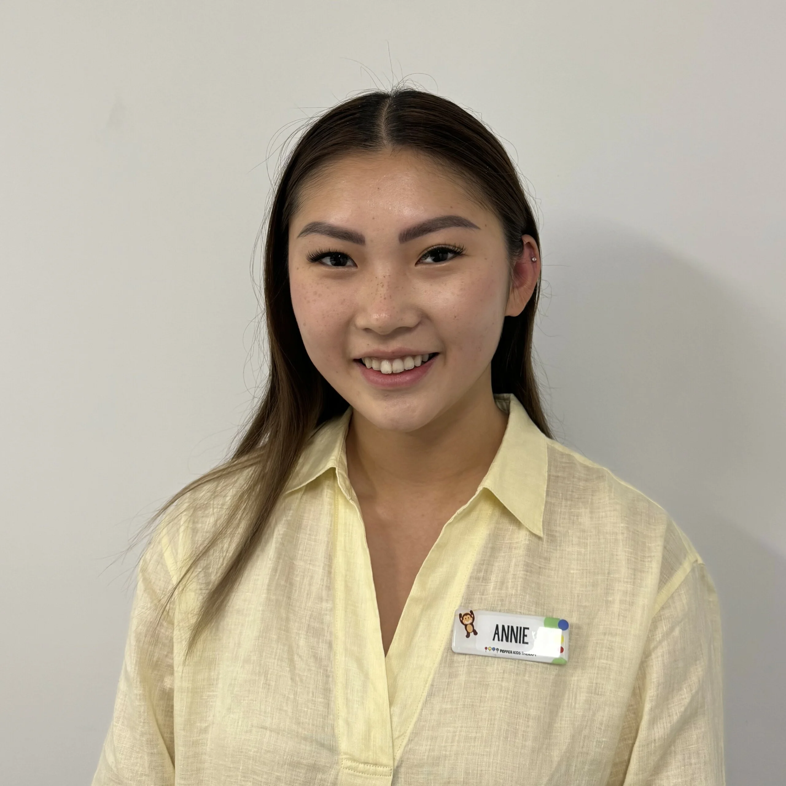 A young woman named Annie, in a yellow shirt, is smiling.