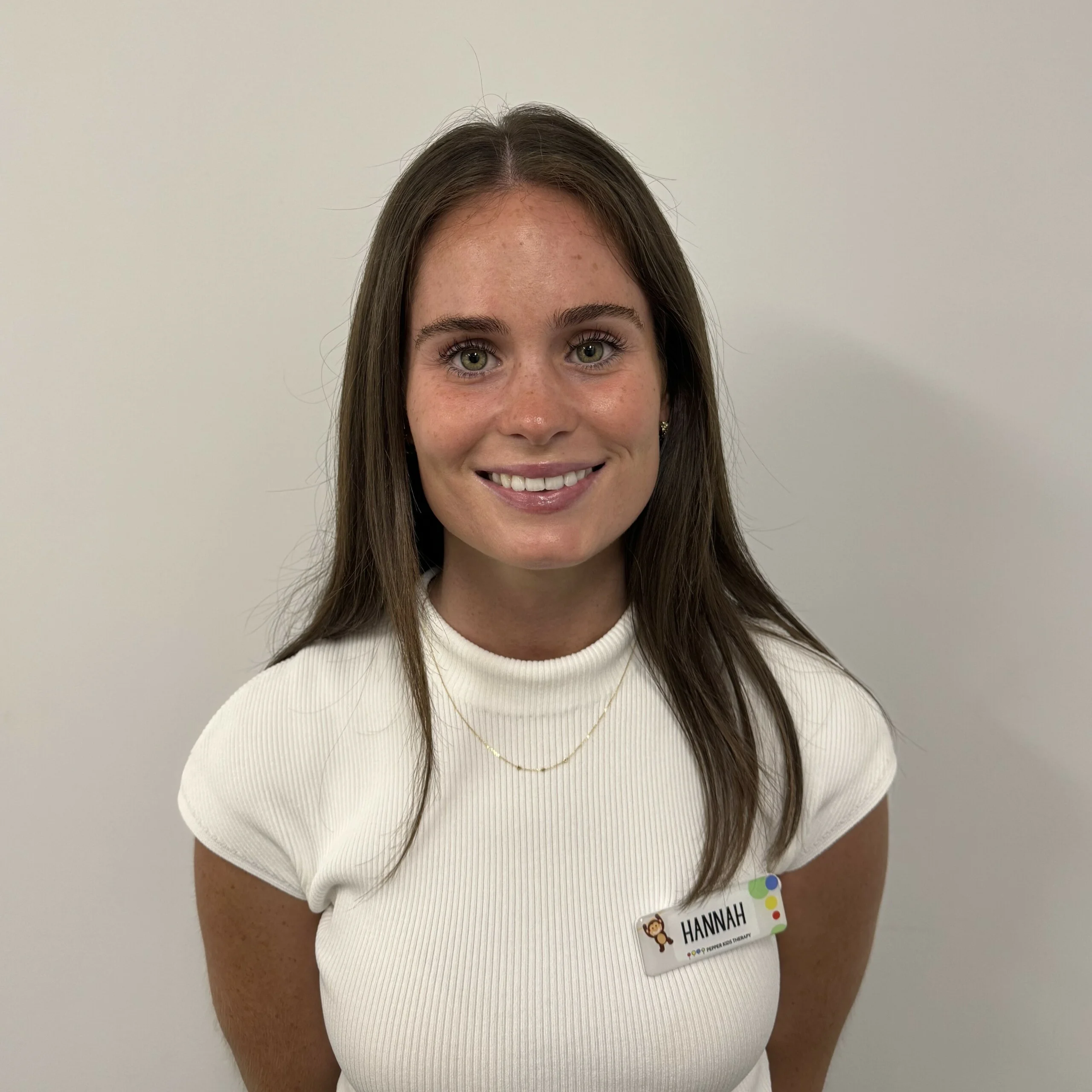 A woman named Hannah is smiling in a white shirt.