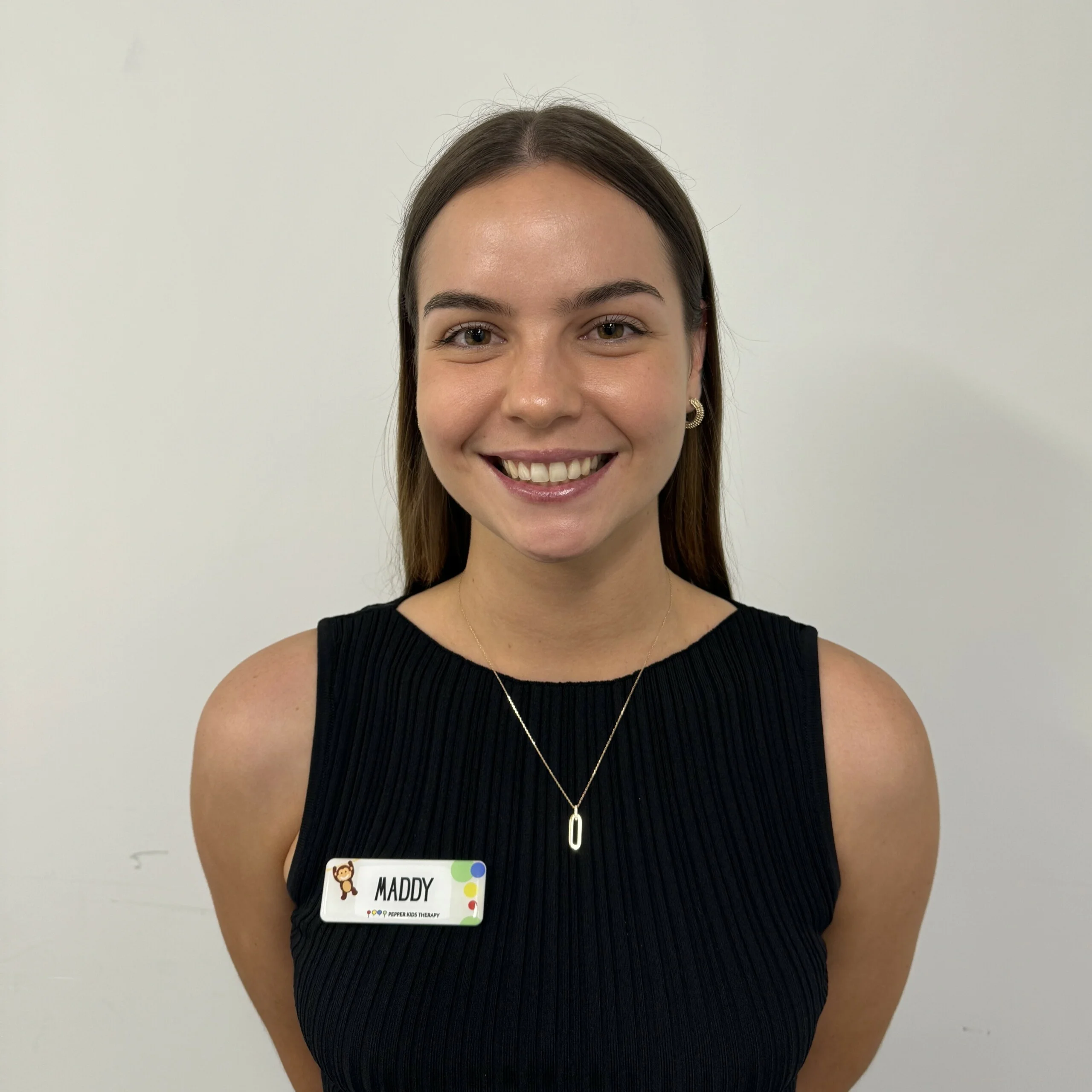 Maddy, a young woman wearing a black shirt with an id tag.